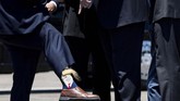 Gubernur Louisiana, Billy Nugesser, menunjukkan kaus kakinya kepada presiden AS Donald Trump setelah orang nomor satu di negeri Paman Sam itu tiba di bandara internasional Chennault. (Photo by Brendan Smialowski / AFP)