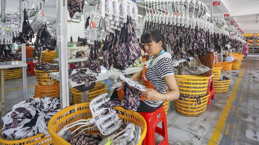 In this Tuesday, May 14, 2019, photo, a worker prepares exercise clothes for export at a clothing factory in Quanzhou in southeastern China's Fujian Province. China's factory output and consumer spending weakened in April as a tariff war with Washington intensified, stepping up pressure on Beijing to shore up economic growth. (Chinatopix via AP)
