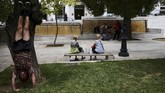Seorang pria berolahraga sementara orang-orang lainnya duduk di alun-alun Syntagma di Athena, Yunani. (REUTERS/Constantina Peppa)