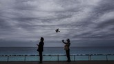 Seorang perempuan mengambil gambar di depan laut Mediterrania di kota Nice, Perancis. (Photo by VALERY HACHE / AFP)