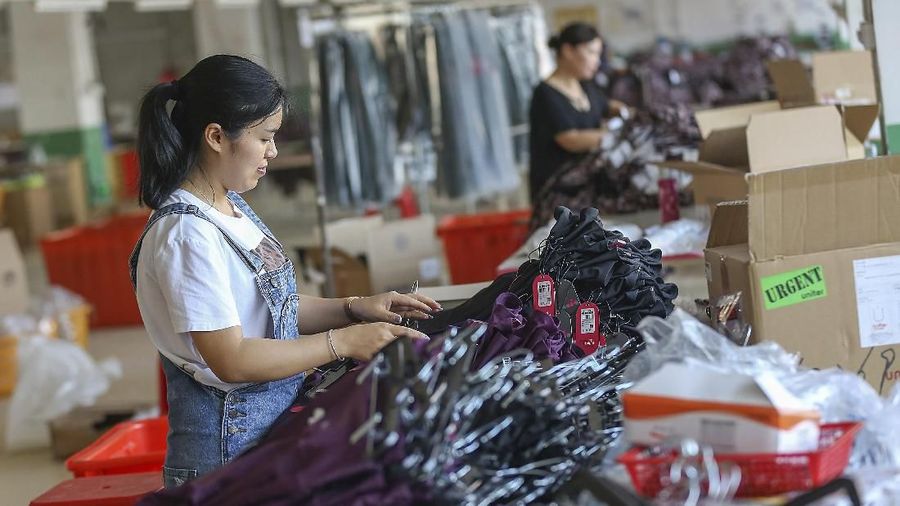 In this Tuesday, May 14, 2019, photo, a worker prepares exercise clothes for export at a clothing factory in Quanzhou in southeastern China's Fujian Province. China's factory output and consumer spending weakened in April as a tariff war with Washington intensified, stepping up pressure on Beijing to shore up economic growth. (Chinatopix via AP)