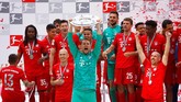 Manuel Neuer mengangkat trofi berbentuk piringan sebagai lambang sukses juara Jerman. (REUTERS/Kai Pfaffenbach)