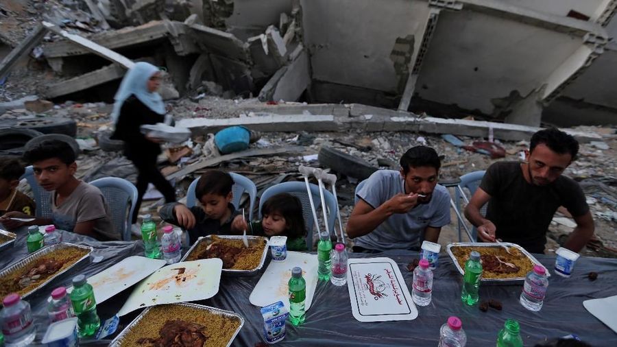Palestinians break their fast by eating the Iftar meals during the holy month of Ramadan, near the rubble of a building recently destroyed by Israeli air strikes, in Gaza City May 18, 2019. REUTERS/Ibraheem Abu Mustafa