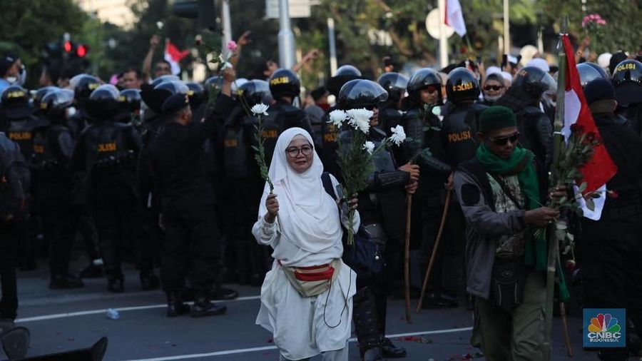 Dalam aksinya mereka membagi-bagikan bunga kepada polisi yang berjaga.