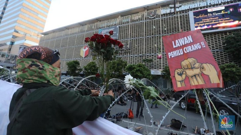 Dalam aksinya mereka membagi-bagikan bunga kepada polisi yang berjaga.