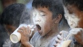 Anak-anak mencoba mengosongkan gelas berisi tepung dengan sebuah sedotan dalam fastival Feast Day of St. Rita of Cascia di Manila. (AFP/Noel Celis)