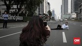 Karyawan menyempatkan diri berfoto di ruas jalan yang sepi di kawasan MH Thamrin, Jakarta, Senin, 27 Mei 2019. Hari ini merupakan hari pertama kerja setelah diliburkan pada 21 sampai 24 Mei pekan lalu. (CNNIndonesia/Safir Makki)
