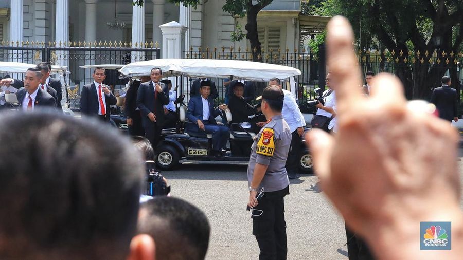 Dengan mengenakan jas berwarna hitam dan memakai peci, Jokowi menyapa warganya yang telah lama mengantre di Monas