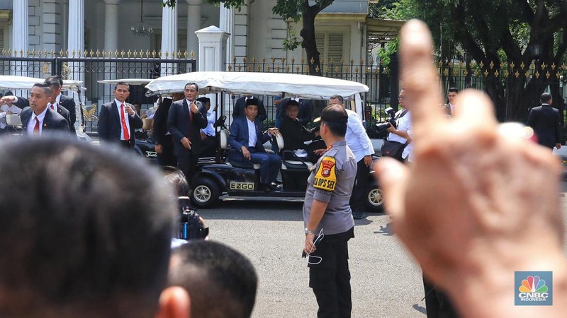 Dengan mengenakan jas berwarna hitam dan memakai peci, Jokowi menyapa warganya yang telah lama mengantre di Monas