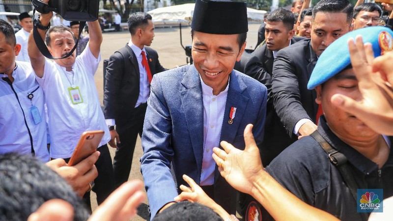 Dengan mengenakan jas berwarna hitam dan memakai peci, Jokowi menyapa warganya yang telah lama mengantre di Monas
