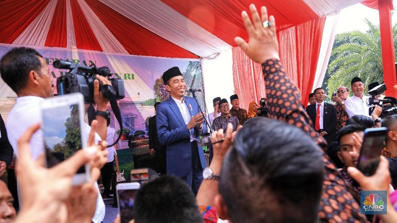 Dengan mengenakan jas berwarna hitam dan memakai peci, Jokowi menyapa warganya yang telah lama mengantre di Monas