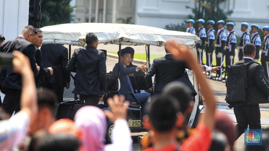 Dengan mengenakan jas berwarna hitam dan memakai peci, Jokowi menyapa warganya yang telah lama mengantre di Monas
