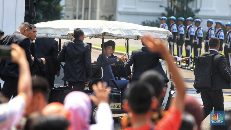 Dengan mengenakan jas berwarna hitam dan memakai peci, Jokowi menyapa warganya yang telah lama mengantre di Monas