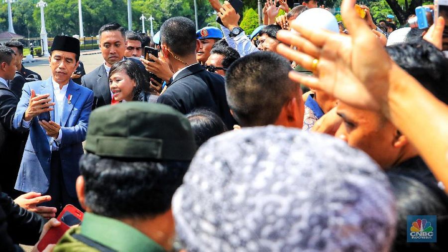Dengan mengenakan jas berwarna hitam dan memakai peci, Jokowi menyapa warganya yang telah lama mengantre di Monas