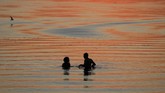 Dua orang menikmati senja di suatu danau di Minsk, Belarusia. (REUTERS/Vasily Fedosenko)