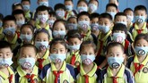 Siswa sekolah dasar mengenakan masker dengan simbol