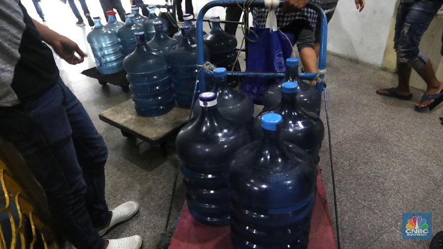 Pedagang air galon membawa galon yang sudah diisi penuh untuk dijual ke warga apartemen di Kawasan Pluit, Jakarta, Rabu (12/6). Banyak penghuni apartemen di kawasan tersebut menggunakan air galon isi ulang untuk mandi. Mumun seorang pembantu rumah tangga mengatakan majiakannya bisa menkonsumsi air galon sehari 4-5 galon untuk mandi dan cuci piring. Harga galon isi ulang ia beli seharga Rp 3500 yang berasal dari air pam, Rp 7000 untuk galon isi ulang untuk galon asli Rp.20.000. Banyak penghuni apartmen menggunakan air galon karena air yang mereka tempati kadang bau dan kotor. (CNBC Indonesia/Muhammad Sabki)