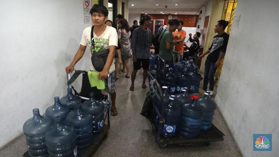 Pedagang air galon membawa galon yang sudah diisi penuh untuk dijual ke warga apartemen di Kawasan Pluit, Jakarta, Rabu (12/6). Banyak penghuni apartemen di kawasan tersebut menggunakan air galon isi ulang untuk mandi. Mumun seorang pembantu rumah tangga mengatakan majiakannya bisa menkonsumsi air galon sehari 4-5 galon untuk mandi dan cuci piring. Harga galon isi ulang ia beli seharga Rp 3500 yang berasal dari air pam, Rp 7000 untuk galon isi ulang untuk galon asli Rp.20.000. Banyak penghuni apartmen menggunakan air galon karena air yang mereka tempati kadang bau dan kotor. (CNBC Indonesia/Muhammad Sabki)