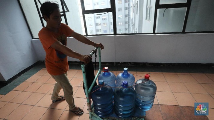 Pedagang air galon membawa galon yang sudah diisi penuh untuk dijual ke warga apartemen di Kawasan Pluit, Jakarta, Rabu (12/6). Banyak penghuni apartemen di kawasan tersebut menggunakan air galon isi ulang untuk mandi. Mumun seorang pembantu rumah tangga mengatakan majiakannya bisa menkonsumsi air galon sehari 4-5 galon untuk mandi dan cuci piring. Harga galon isi ulang ia beli seharga Rp 3500 yang berasal dari air pam, Rp 7000 untuk galon isi ulang untuk galon asli Rp.20.000. Banyak penghuni apartmen menggunakan air galon karena air yang mereka tempati kadang bau dan kotor. (CNBC Indonesia/Muhammad Sabki)