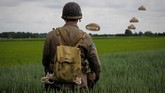 Seorang pria berpakaian sebagai tentara perang melihat ke arah Brigade Udara 16 Inggris dan juga Brigade Perancis yang sedang melompat ke arah Sannerville, barat laut Perancis, sebelum peringatan 75 tahun D-Day, atau ketika sekutu mendarat di Normandy pada Perang Dunia II. (AFP/Guillaume Souvant)