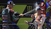 Pebalap Yamaha Petronas Fabio Quartararo menyemprotkan sampanye ke Marc Marquez di atas podium MotoGP Catalunya 2019. Ini adalah kali pertama Quartararo naik podium di MotoGP. (LLUIS GENE / AFP)