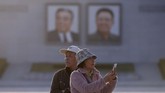 Sepasang turis China berfoto di kawasan alun-alun Kim Il Sung di Pyongyang, Korea Utara. Kesamaan sejarah membuat China dan Korea Utara akur, hingga kini menular ke jumlah kunjungan turisnya.