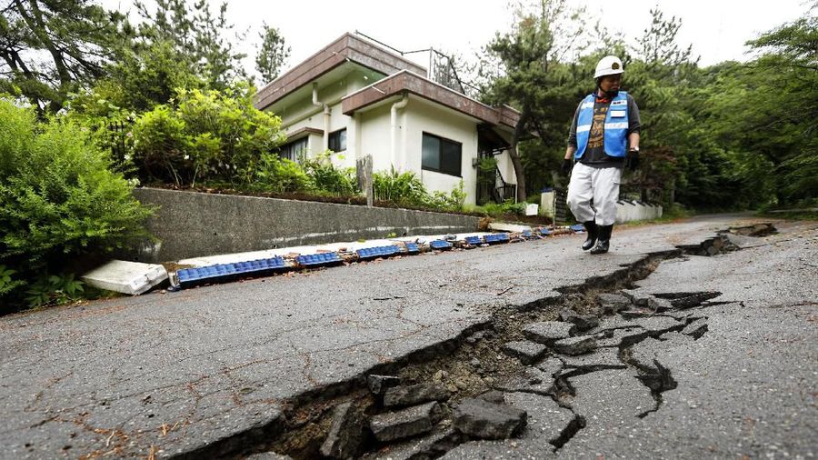 A city official inspects the damage of a road in Tsuruoka, Yamagata prefecture, northwestern Japan, Wednesday, June 19, 2019, after an earthquake. The powerful earthquake jolted northwestern Japan late Tuesday, causing minor injuries and a brief evacuation of coastal homes until the risk of a tsunami passed. (Hironori Asakawa/Kyodo News via AP)