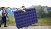 Seorang pria rela mengangkat sebuah kasur portabel demi kenyamanan menonton Festival Glastonbury. (REUTERS/Henry Nicholls)