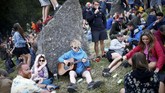 Tak sedikit yang memilih bersantai saja sembari berkumpul dan memainkan musik di atas rumput, di antara batu-batu besar di peternakan Worthy di Somerset. (REUTERS/Henry Nicholls)