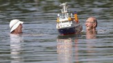 Pasangan berenang di samping perahu buatan di suatu danau di Ertingen, Jerman. Gelombang panas yang menyerang Jerman dan Eropa membawa suhu panas hingga 40 derajat celcius. (Thomas Warnack/dpa via AP)