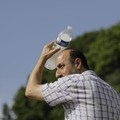 A man uses a cool bottle of water to cool off in the Trocadero gardens in Paris, Friday, June 28, 2019. Schools are spraying kids with water and nursing homes are equipping the elderly with hydration sensors as France and other nations battle a recor
