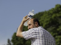 A man uses a cool bottle of water to cool off in the Trocadero gardens in Paris, Friday, June 28, 2019. Schools are spraying kids with water and nursing homes are equipping the elderly with hydration sensors as France and other nations battle a recor
