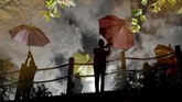 Bayangan pasukan tari tercermin di air. Mereka sedang berpose untuk fotografer-fotografer media di ajang