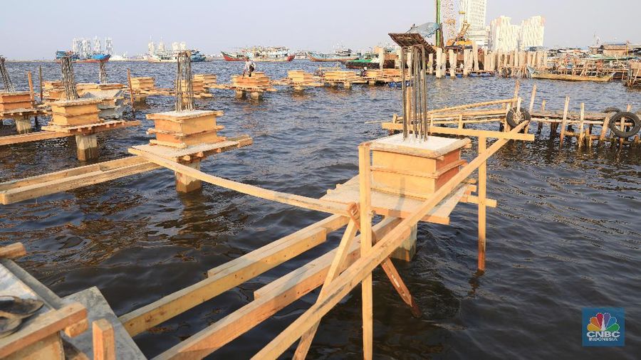 Pekerja menyelesaikan pembangunan dermaga yang dilengkapi pemecah ombak di Kawasan Kali Adem, Muara Angke, Jumat (5/7/2019).