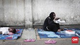 Pencari suaka asal Somalia menikmati nasi kotak di trotoar di kawasan Kebon Sirih, Jakarta, Jumat, 5 Juli 2019. (CNNIndonesia/Safir Makki)