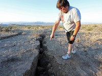 A man looks into a fissure that opened in the desert during a powerful earthquake that struck Southern California, near the city of Ridgecrest, California, U.S., July 4, 2019. REUTERS/David McNew