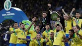 Kapten timnas Brasil Dani Alves yang dinobatkan sebagai pemain terbaik turnamen mengangkat trofi Copa America 2019 yang disambut gembira oleh rekan-rekan setimnya usai mengalahkan timnas Peru 3-1. (REUTERS/Ueslei Marcelino)