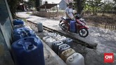 Anwar menggunakan motor untuk mengangkut jeriken air yang diambil dari MCK umum di Desa Ridogalih, Cibarusah, Kabupaten Bekasi, Rabu (10/7). (CNNIndonesia/Safir Makki)