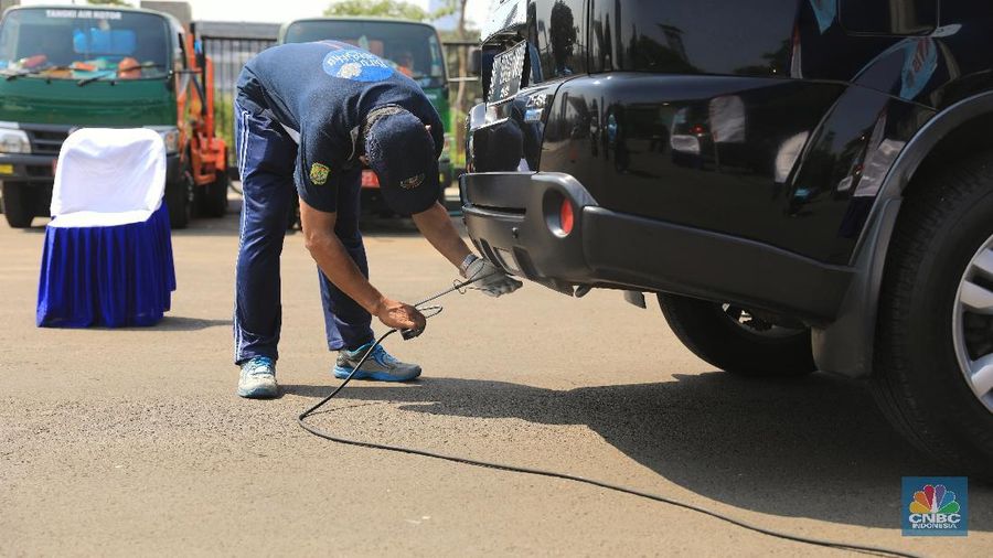 Petugas Suku Dinas Lingkungan Hidup melakukan uji emisi gas buangan kendaraan bermotor roda empat di Kawasan Senayan,  Selasa (16/7).