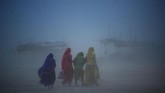 Para perempuan India berjalan melewati badai debu di Sangam, atau delta Sungai Gangga, Yamuna dan Saraswati di Allahabad. (Photo by SANJAY KANOJIA / AFP)