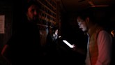Beberapa warga bermain ponsel di sebuah bar selama pemadaman listrik di Caracas, Venezuela 22 Juli 2019. (REUTERS/Manaure Quintero)