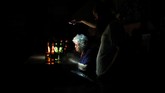Seorang pria menggunakan ponsel untuk menerangi vendor di sebuah bar saat pemadaman listrik di Caracas, Venezuela, 22 Juli 2019. (REUTERS/Manaure Quintero)