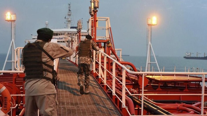 In this Sunday, July 21, 2019 photo, two armed members of Iran's Revolutionary Guard inspect the British-flagged oil tanker Stena Impero, which was seized in the Strait of Hormuz on Friday by the Guard, in the Iranian port of Bandar Abbas. Global stock markets were subdued Monday while the price of oil climbed as tensions in the Persian Gulf escalated after Iran's seizure of a British oil tanker on Friday. (Morteza Akhoondi/Mehr News Agency via AP)