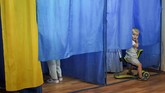 Dari dalam bilik seorang bocah melihat tempat pencoblosan di pemilihan umum anggota parlemen Ukraina di Kiev. (AP/Evgeniy Maloletka)