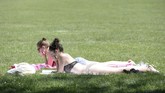 Para wanita muda berjemur di taman di Brussels, Belgia, 23 Juli 2019. (REUTERS/Johanna Geron)
