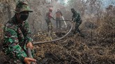 Petugas dari Satgas Karhutla Provinsi Riau berusaha memadamkan bara api yang membakar lahan gambut di Desa Karya Indah, Kabupaten Kampar, Riau, 26 Juli 2019. (ANTARA FOTO/Rony Muharrman)