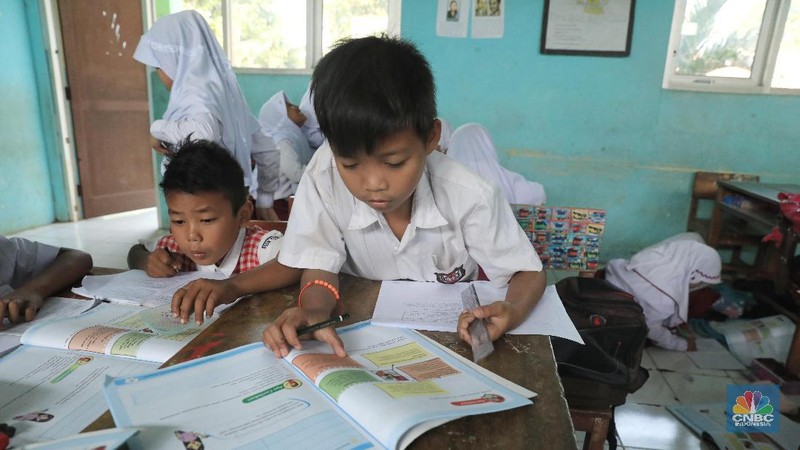 Akibat kekurangan bangku sejumlah siswa terpaksa disekolah tersebut harus duduk satu meja untuk tiga orang.