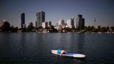 Seorang perempuan bersandar di papan selancar di suatu sungai yang ditinggalkan ketika terjadi gelombang panas di Wina, Austria pada Kamis (25/7). (Reuters/Lisi Niesner).