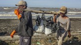 Warga membawa karung berisi pasir yang tercemar tumpahan minyak mentah (Oil Spill) di pesisir Pantai Cemarajaya, Karawang, Jawa Barat. PT Pertamina disebut akan memberi kompensasi kepada nelayan yang terkena dampak kebocoran minyak di Blok ONWJ. (ANTARA FOTO/M Ibnu Chazar)