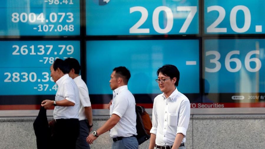 A man paues in front of an electric screen showing Japan's Nikkei share average outside a brokerage in Tokyo, Japan, August 5, 2019.   REUTERS/Issei Kato